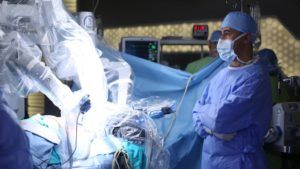 Doctor in surgery room standing next Da Vinci Robot preparing to perform a Prostatectomy